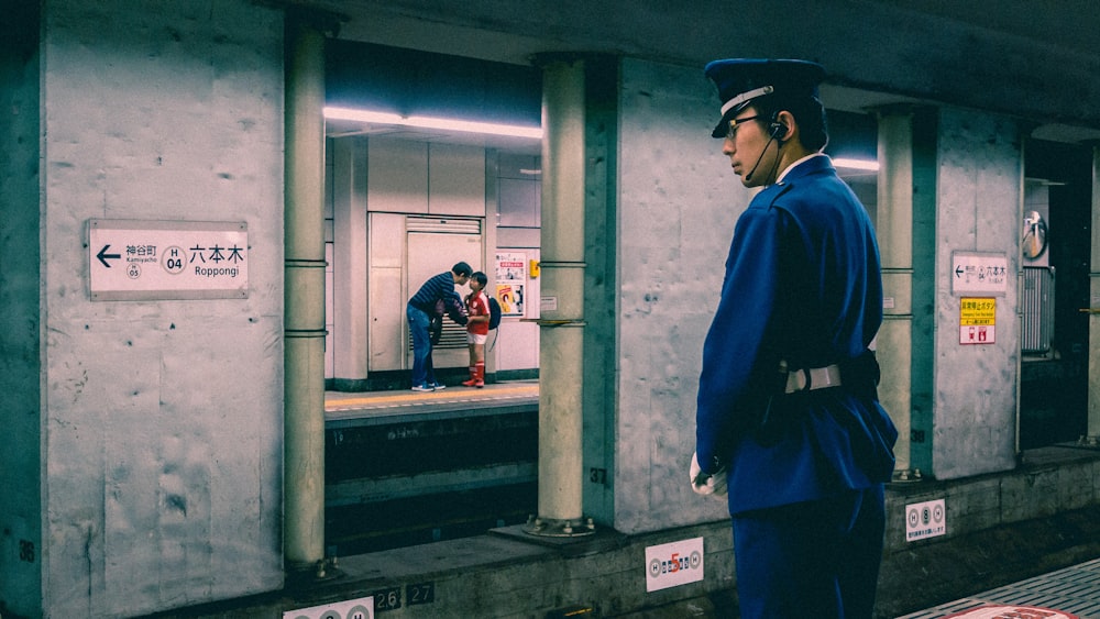 a man in a blue uniform waiting for a train