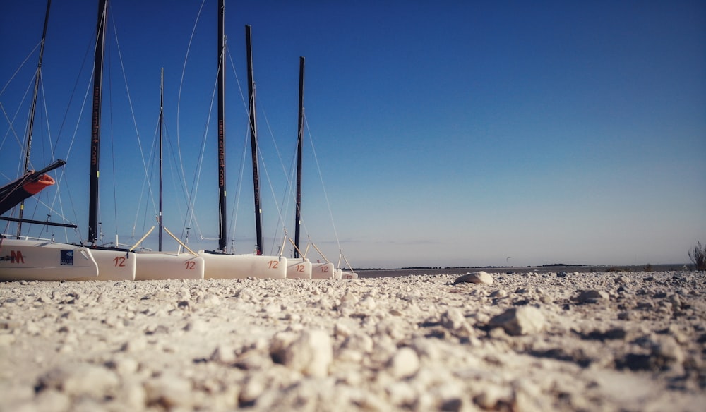 a row of sailboats sitting on top of a sandy beach