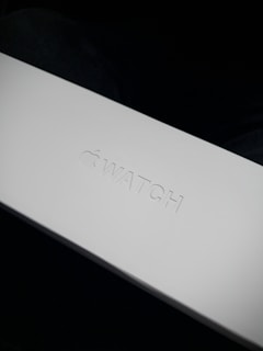 Close-up of a sleek, matte black premium packaging box with subtle embossed details on a pale gray background.