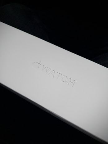 Close-up of a sleek, matte black premium packaging box with subtle embossed details on a pale gray background.