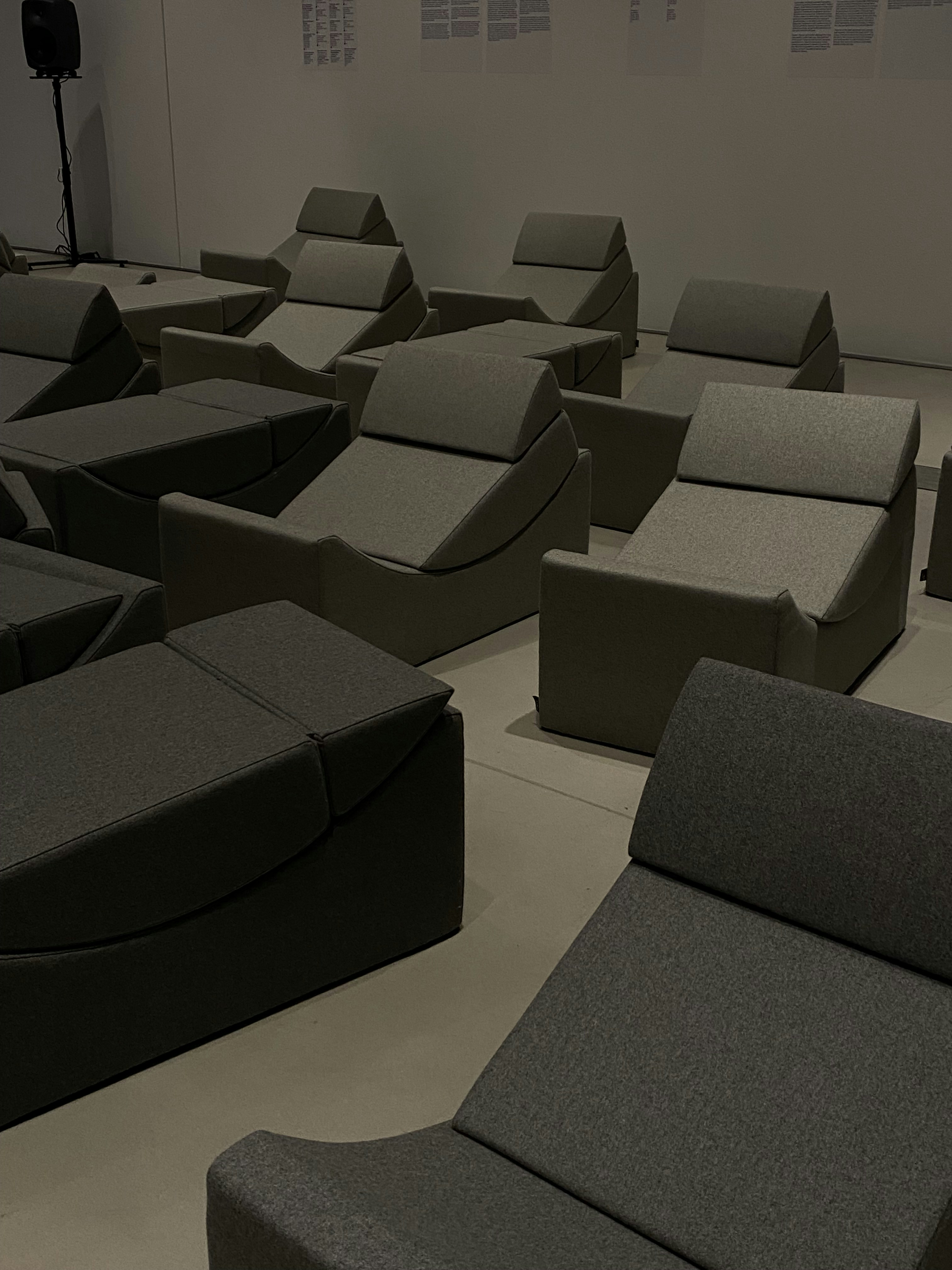 Sleek white upholstered chair in a dim atmospheric room with deep grey walls and subtle ambient lighting