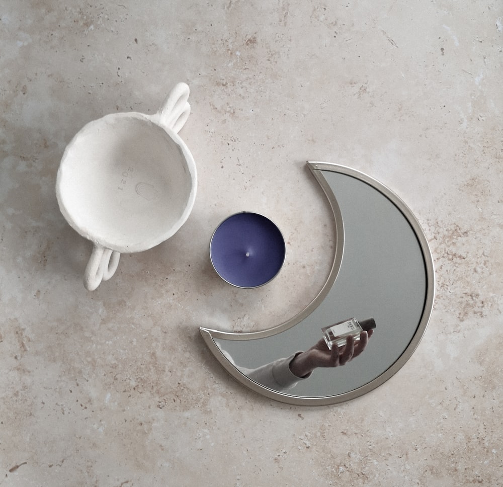 a moon shaped candle holder next to a ceramic bowl