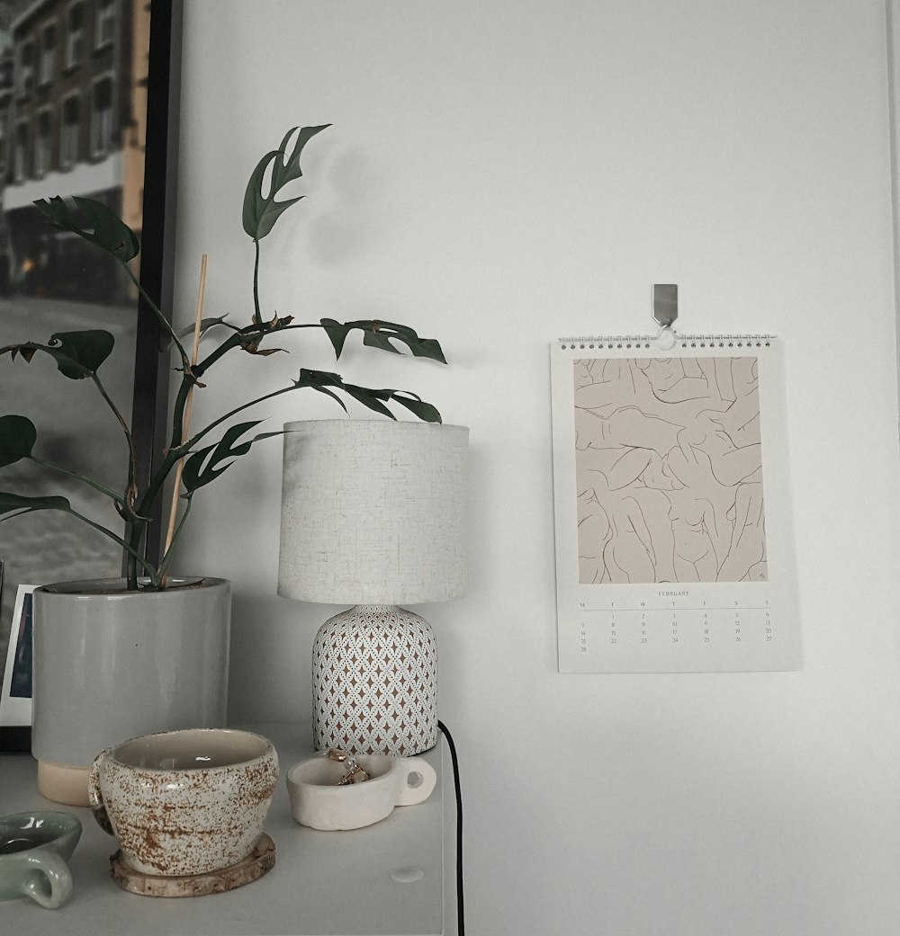 a white table topped with a lamp next to a potted plant