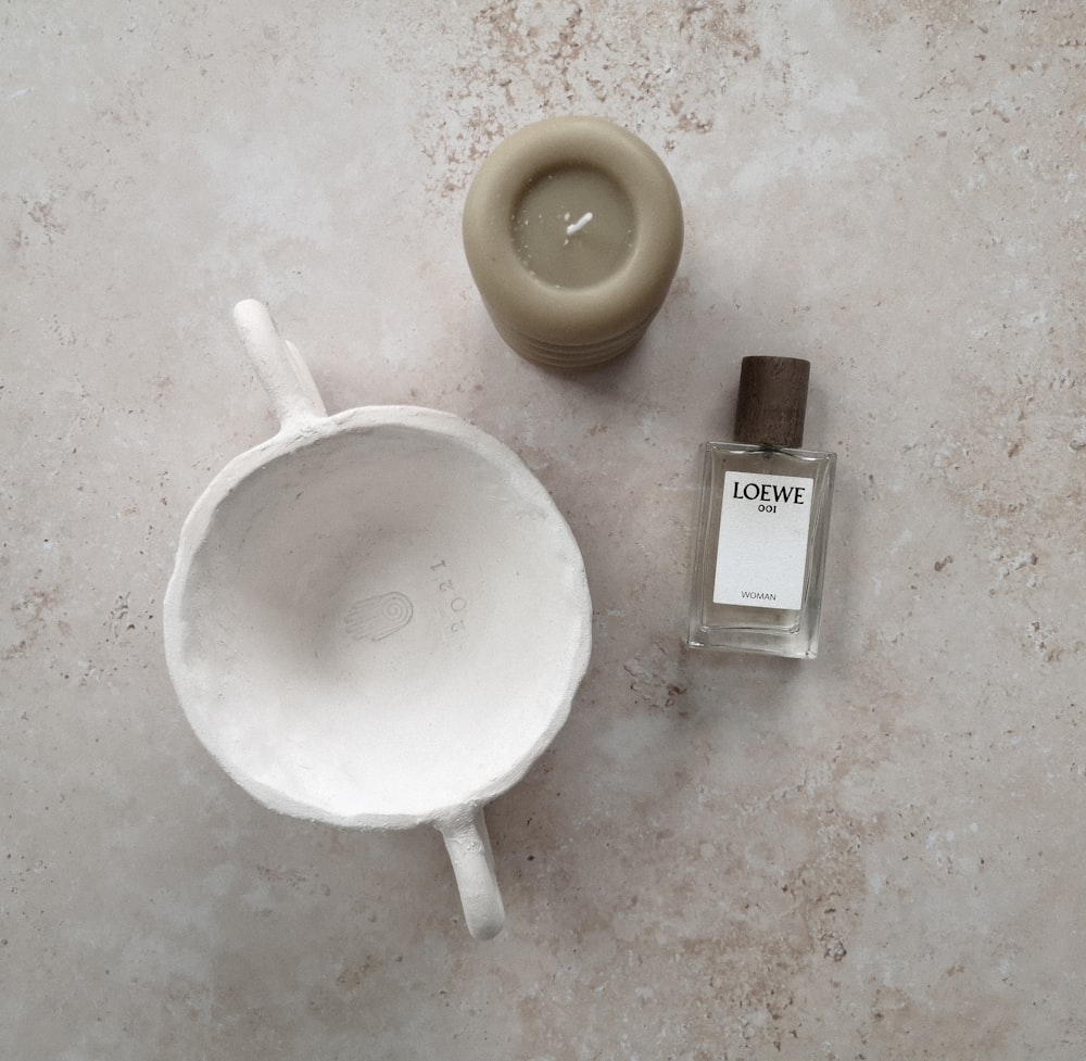a bottle of love perfume next to a ceramic cup
