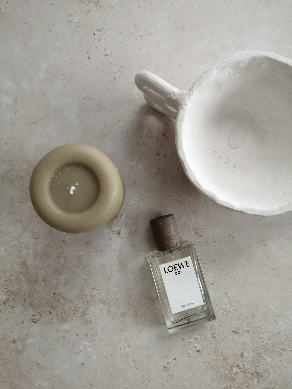 a bottle of cologne next to a white bowl