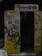 An old photo booth with a worn sign and partially obscured by graffiti. The exterior is covered in various stickers, drawings, and colorful graffiti including phrases and designs. The interior appears dark, with a curtain hanging inside. Snow is visible on the ground in front.