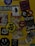 A collection of various stickers arranged on a yellow surface. The stickers include images of a woman, abstract designs, brand logos, and cartoon characters, along with text in different fonts.