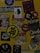 A collection of various stickers arranged on a yellow surface. The stickers include images of a woman, abstract designs, brand logos, and cartoon characters, along with text in different fonts.