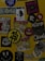 A collection of various stickers arranged on a yellow surface. The stickers include images of a woman, abstract designs, brand logos, and cartoon characters, along with text in different fonts.