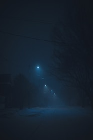 a dark street at night with a street light in the distance