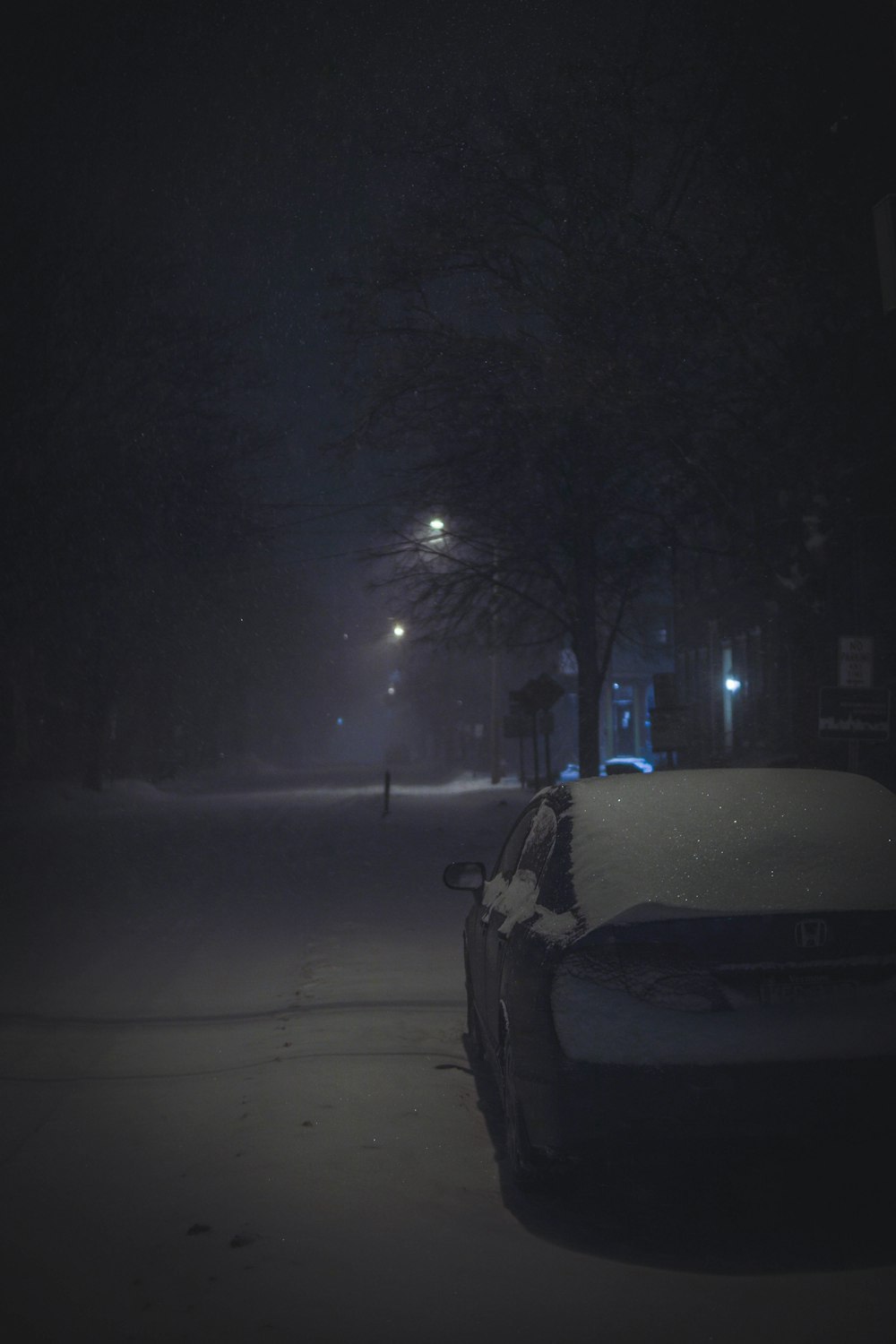 Un coche aparcado en una calle nevada por la noche