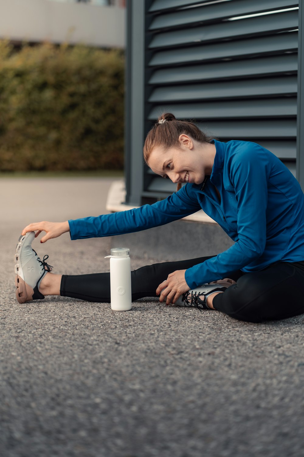 a woman sitting on the ground with her foot on a cup