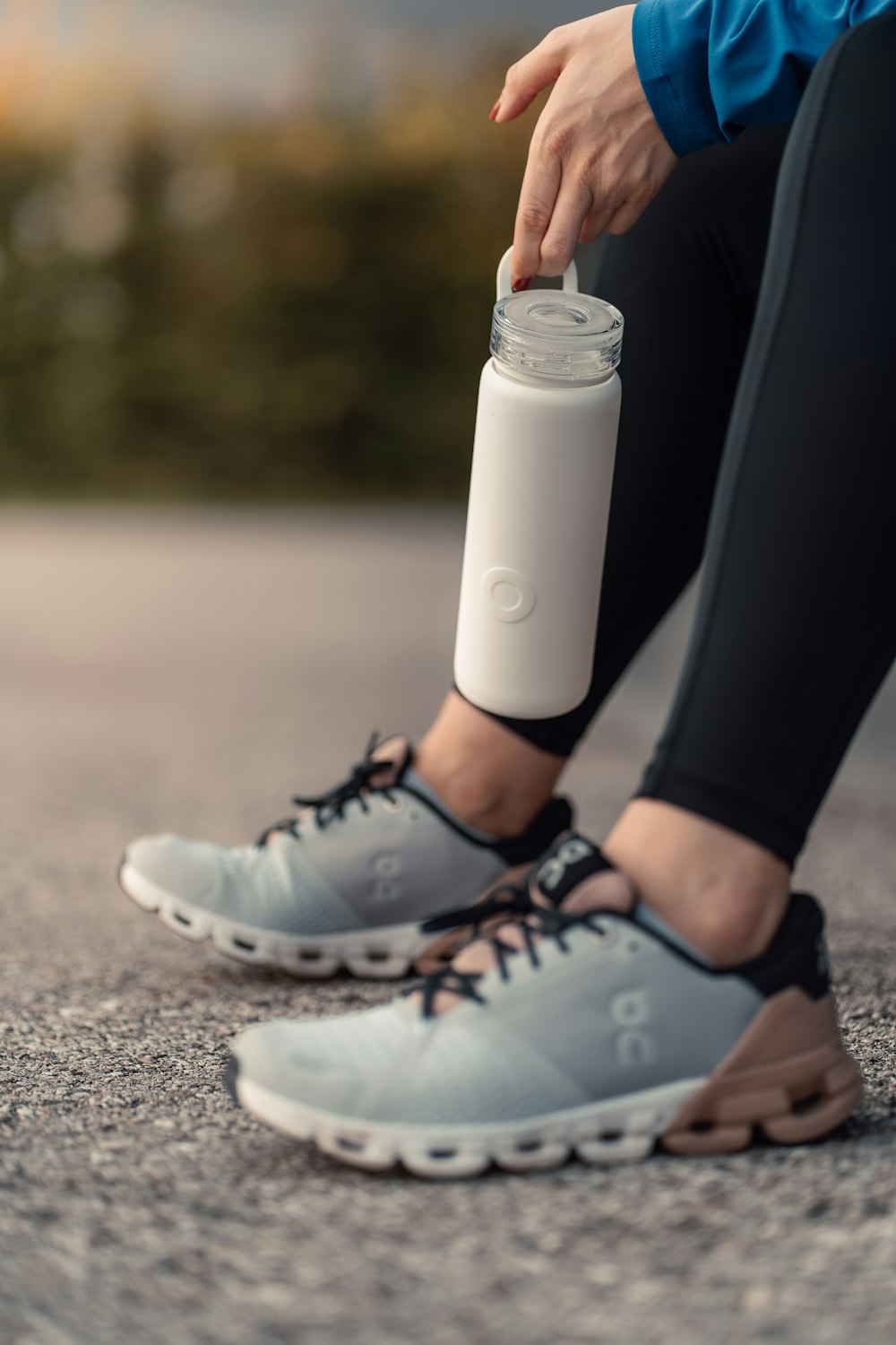 a person is holding a water bottle and tying it to a shoe