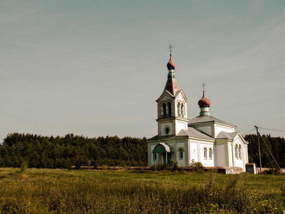 a white church with a red steeple in a field