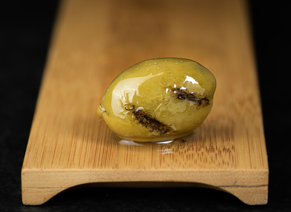 a green apple sitting on top of a wooden cutting board