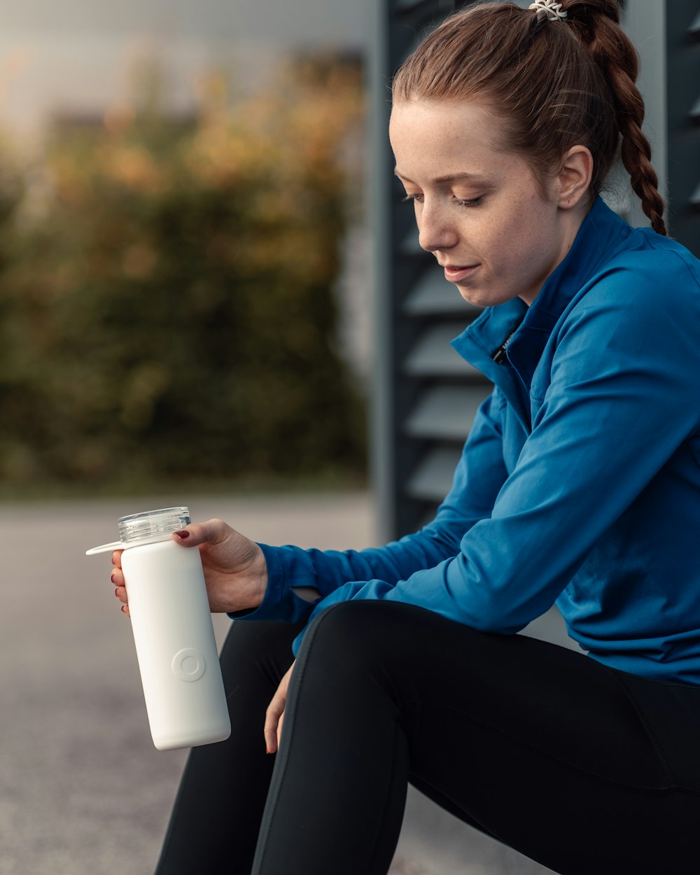 a woman sitting on the ground holding a water bottle