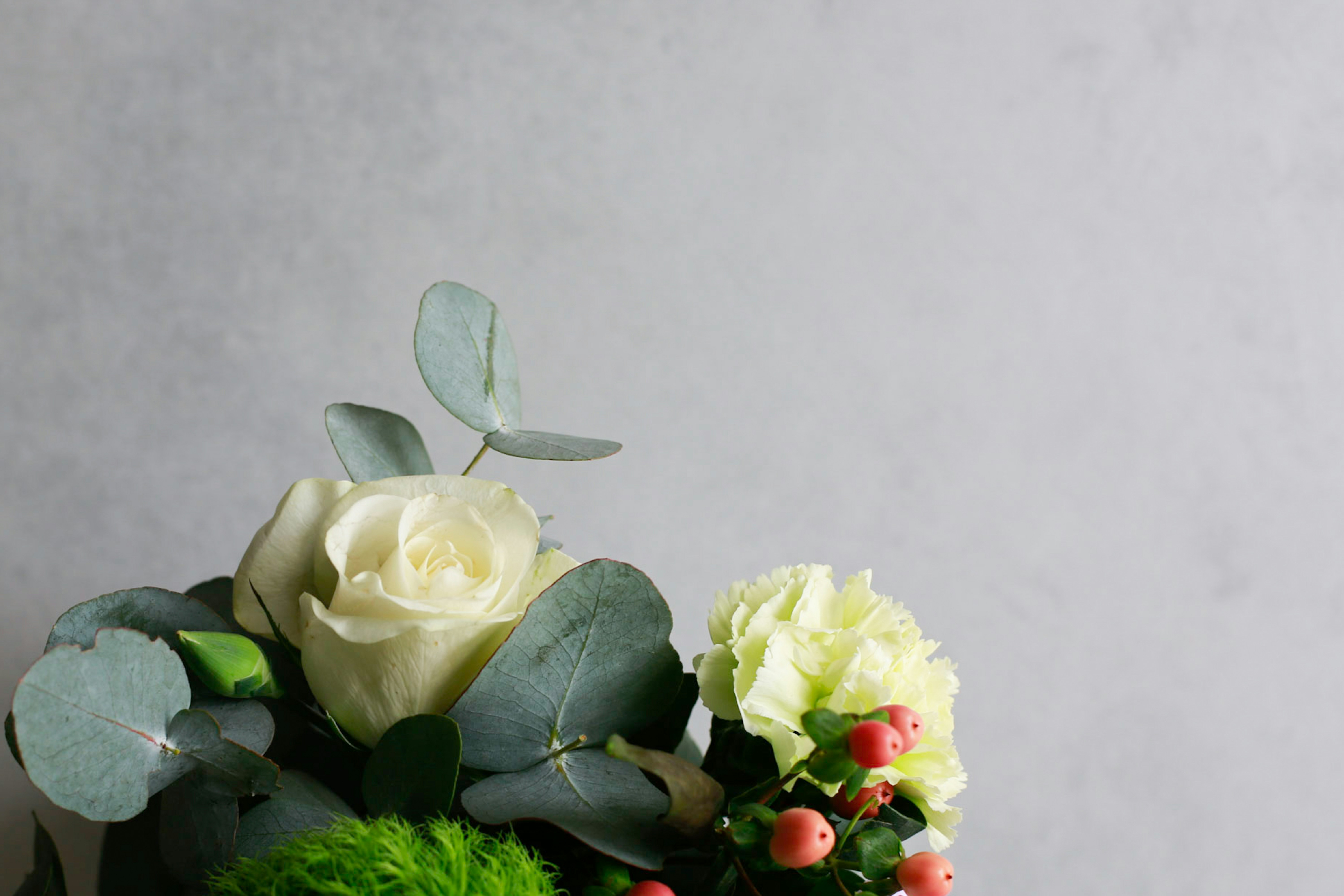 a vase filled with flowers and greenery on top of a table