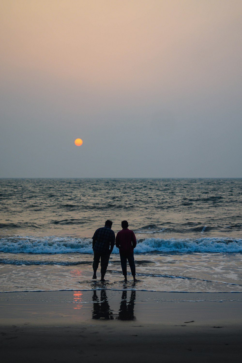 a couple of people standing on top of a beach