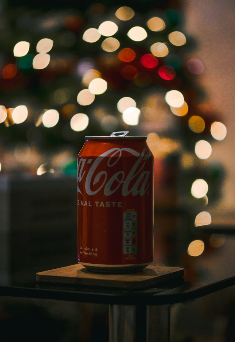 a can of coca - cola sitting on a table in front of a christmas tree