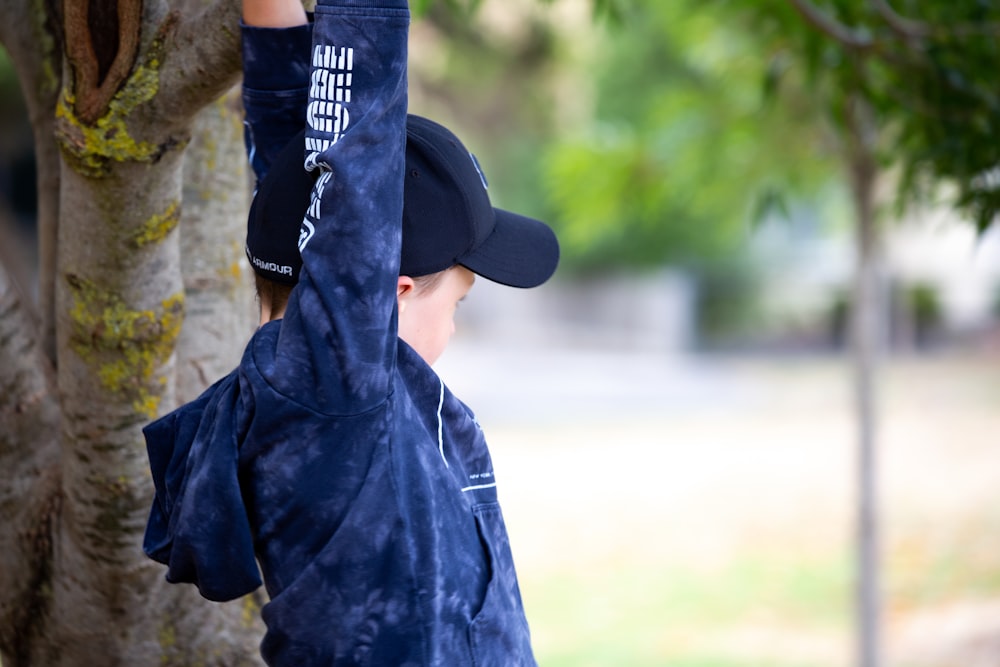 a young boy reaching up to a tree