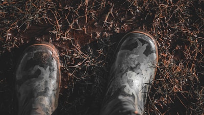Durable military boots standing firmly on muddy ground