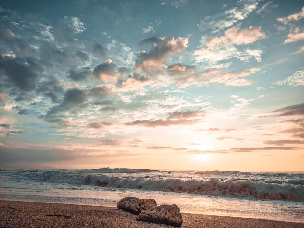 a couple of rocks sitting on top of a sandy beach