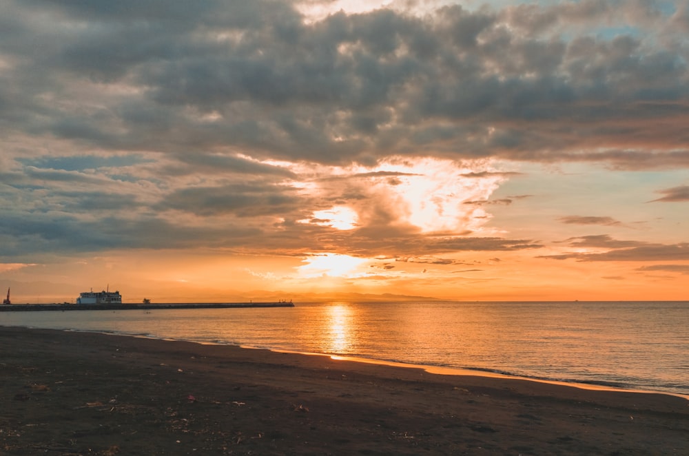 the sun is setting over the ocean on the beach