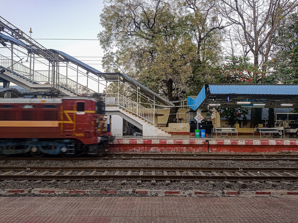 a red train traveling past a train station