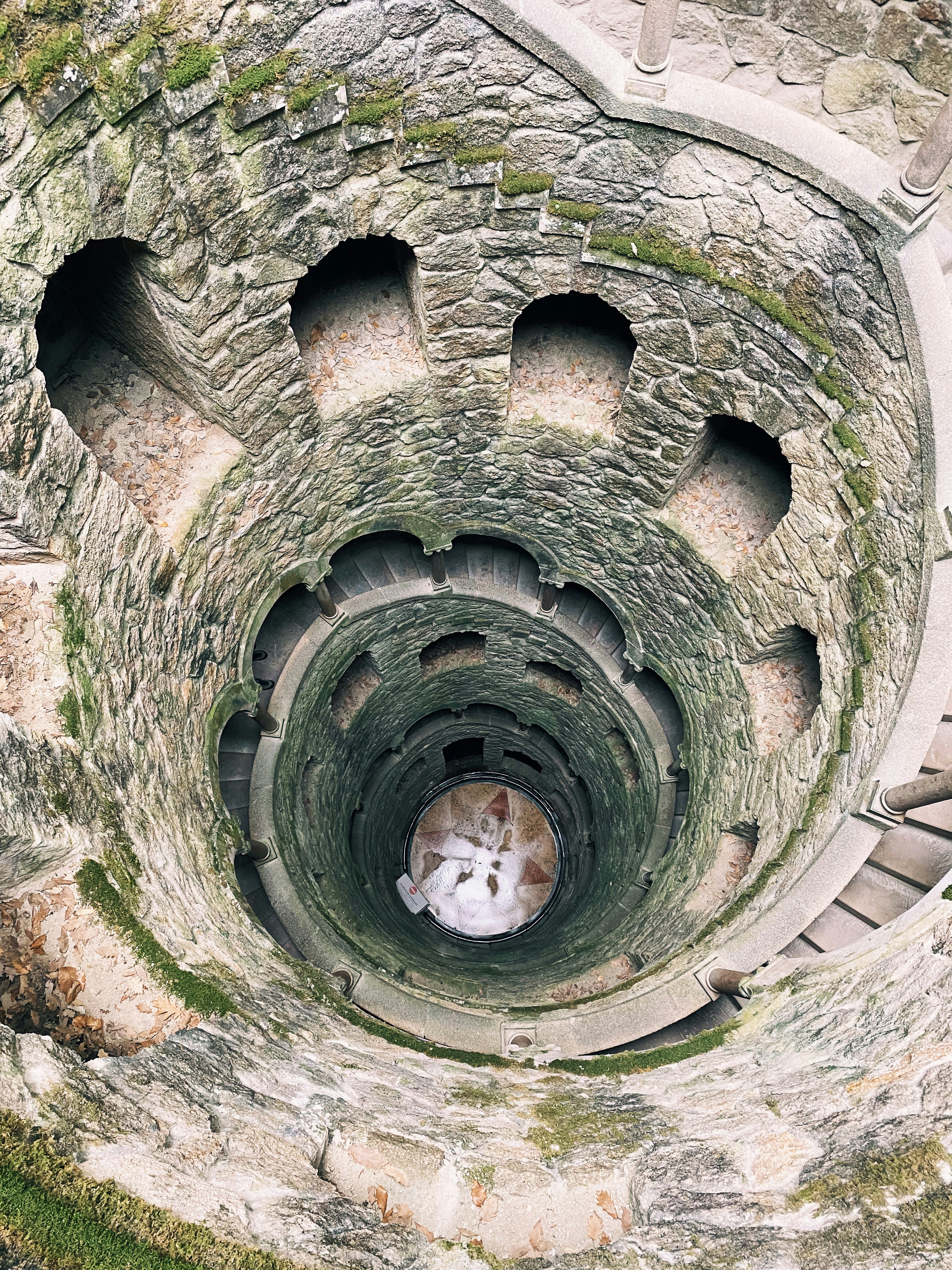 Image from the top, looking in, of a hand hewn rock masonry spiral staircase by Warren Sammut from Unsplash