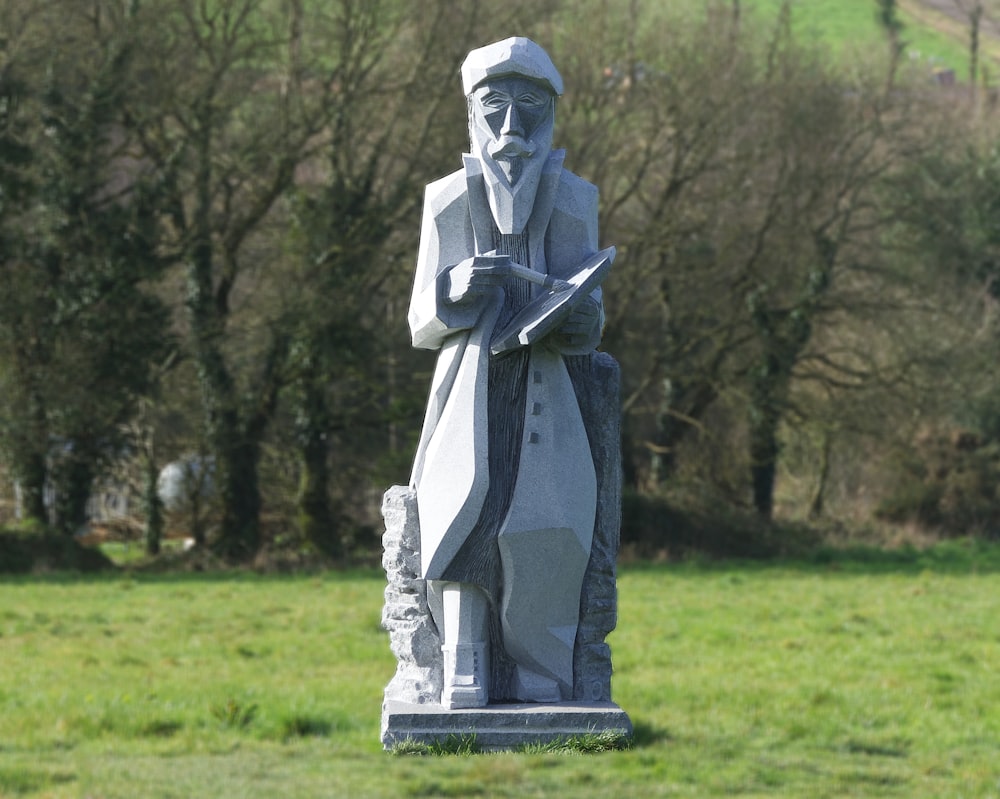 a statue of a man holding a book in a field