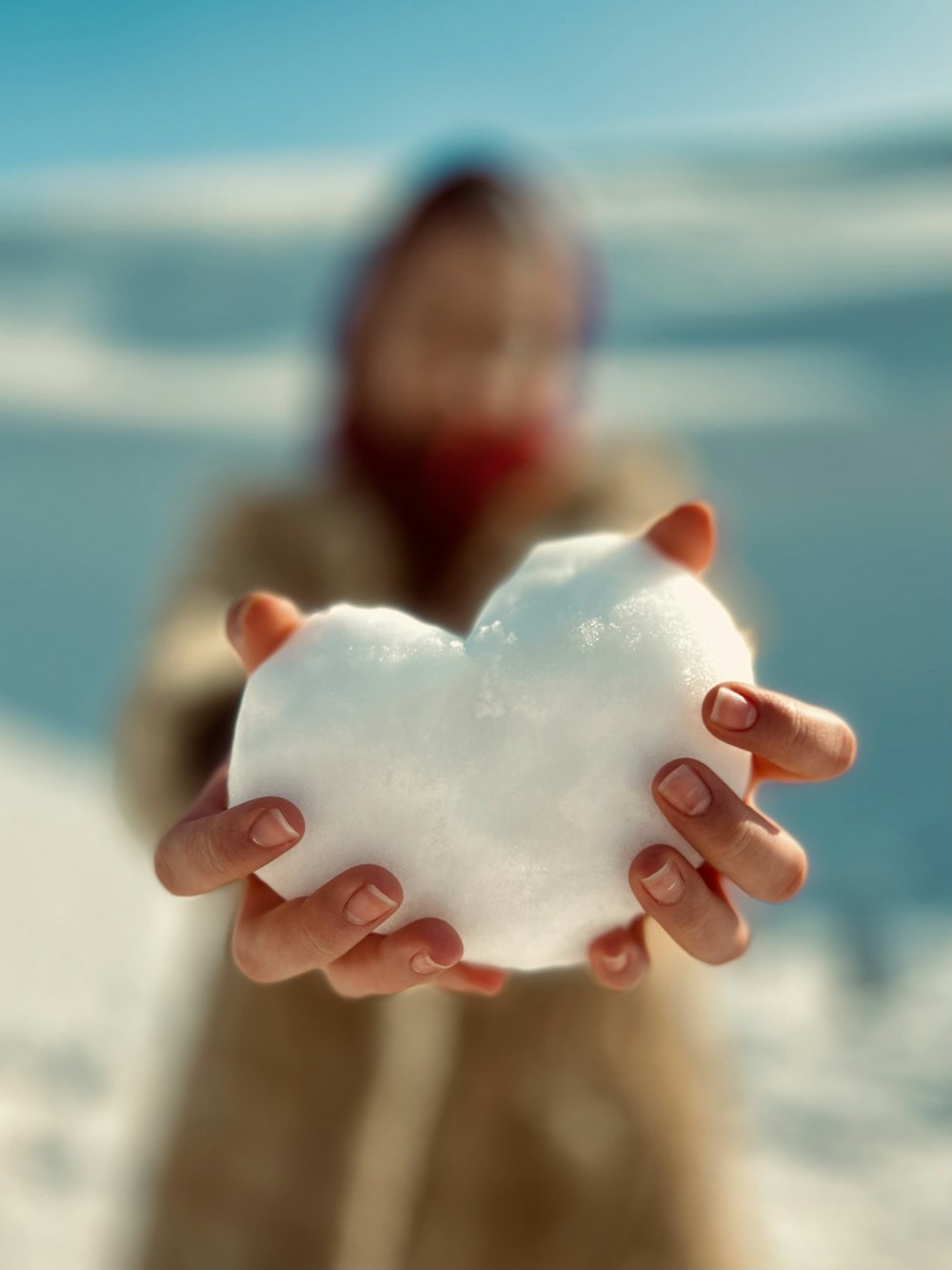 a person holding a heart shaped snowball in their hands