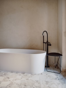 a white bath tub sitting next to a black stool