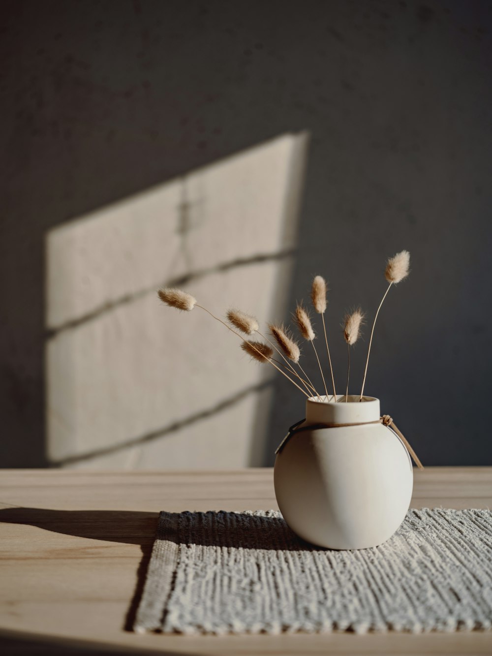 eine weiße Vase auf einem Holztisch
