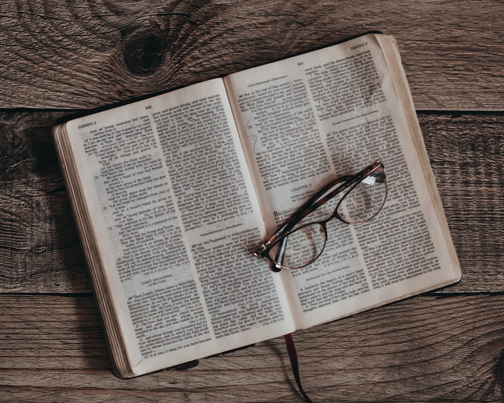 an open book with glasses on top of it