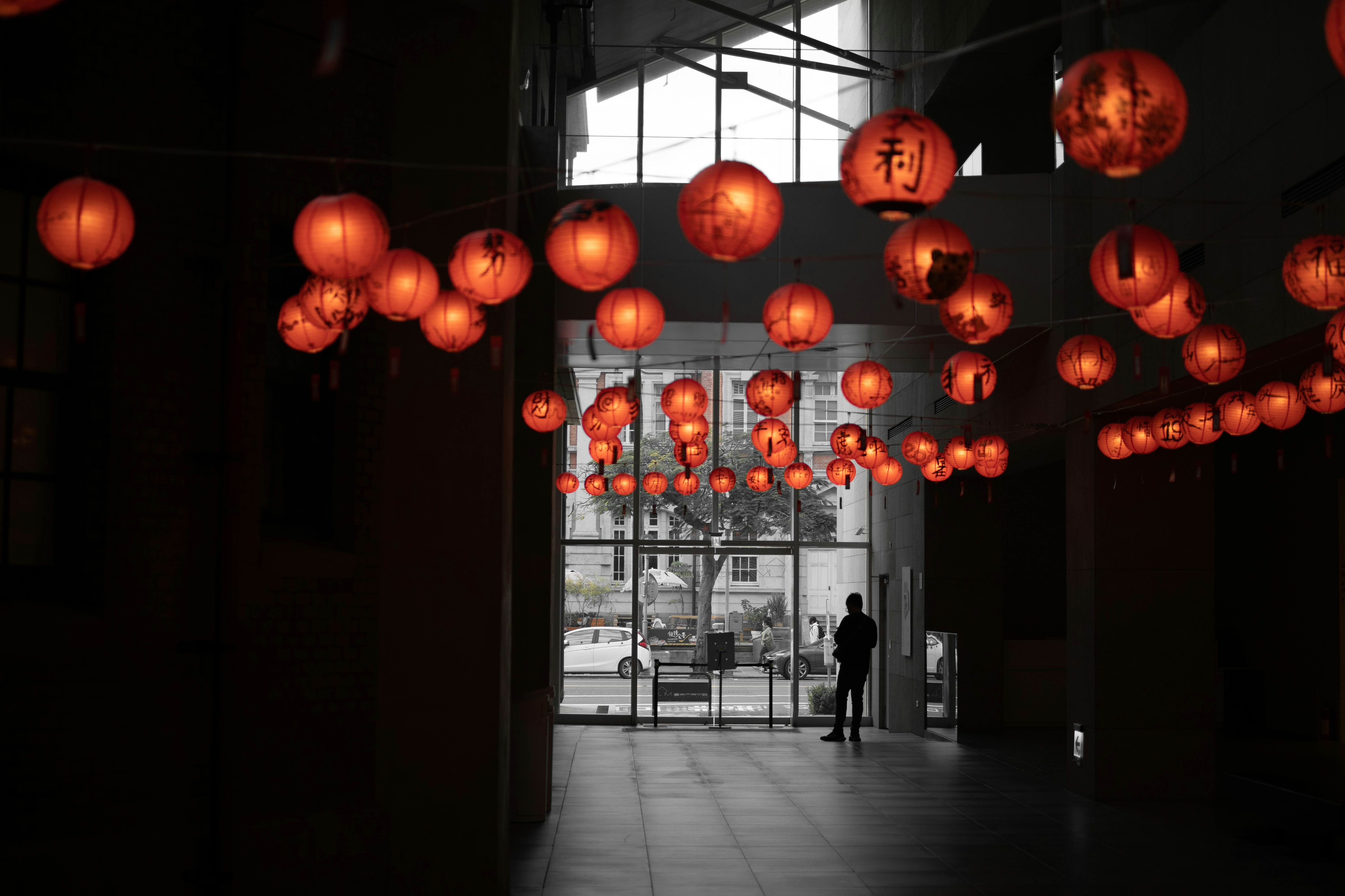 a man standing in front of a building with lots of lanterns hanging from the ceiling