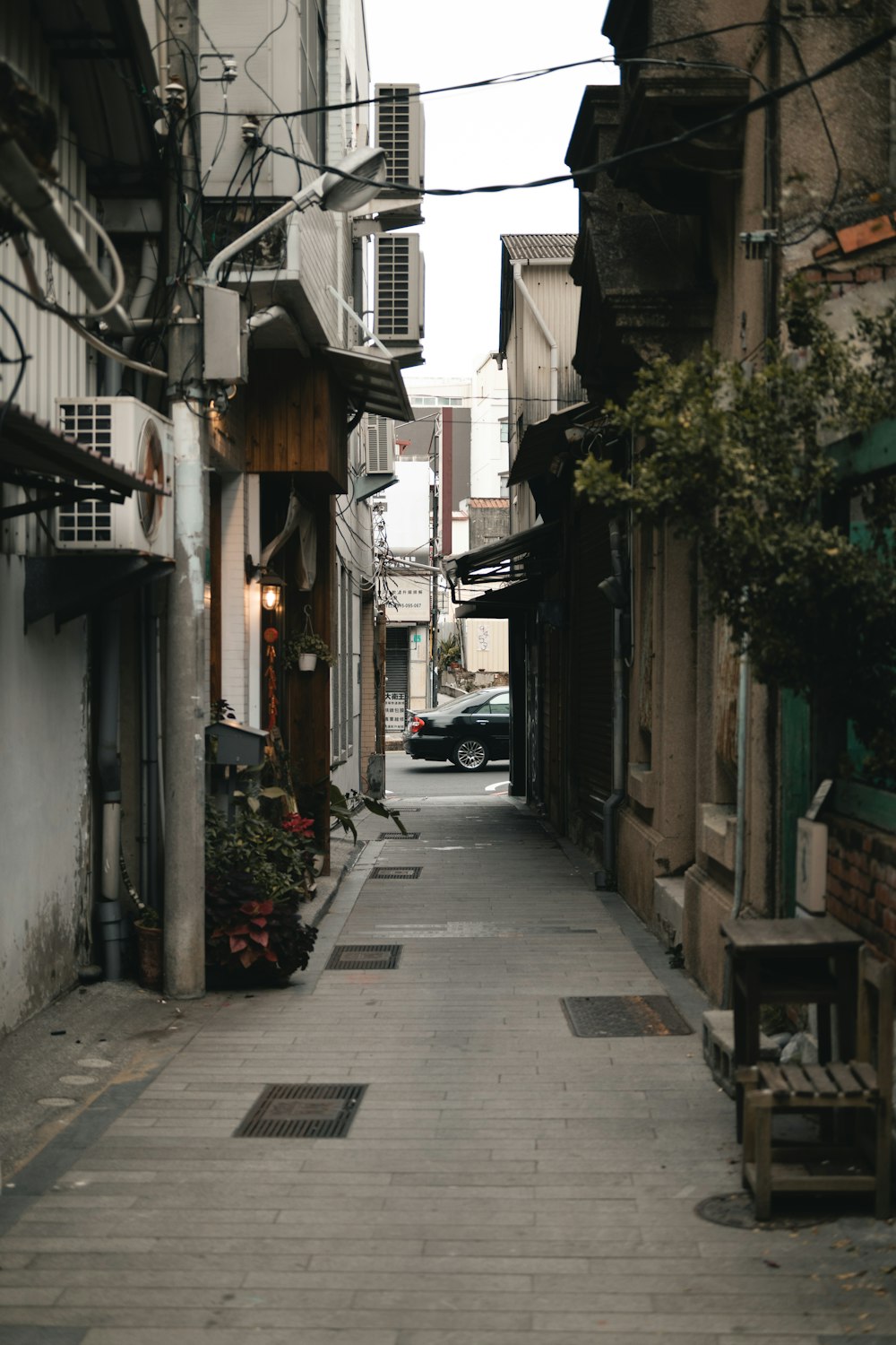 a narrow street with a bench and a car parked on the side of it