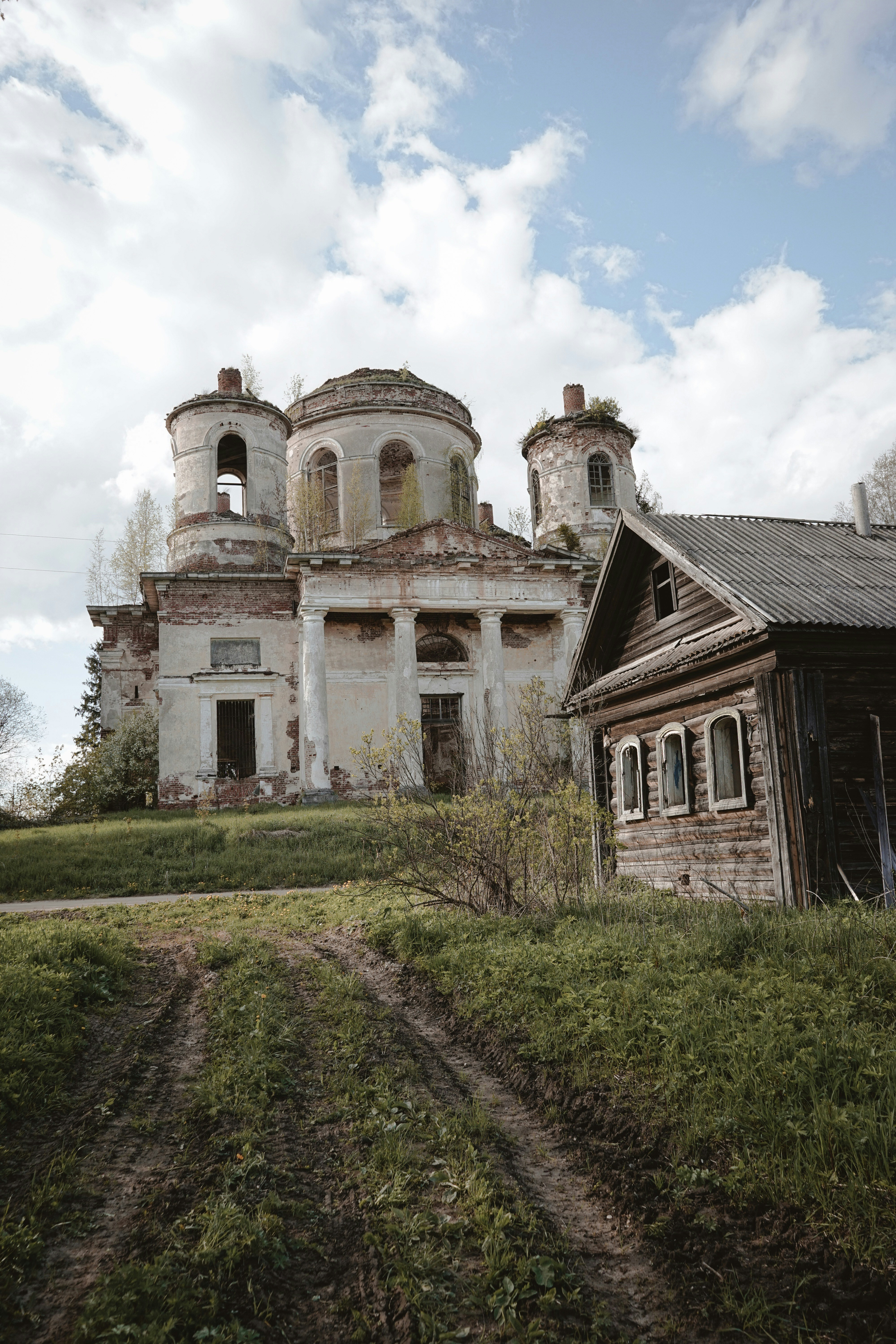 an old run down house with a dirt path in front of it