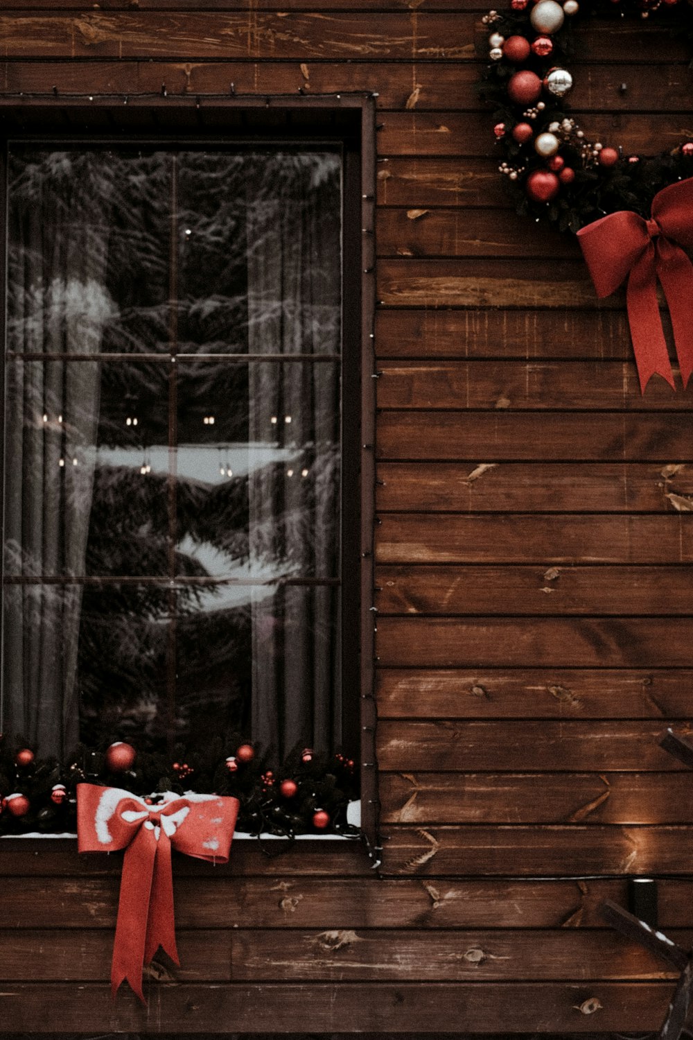 a window with a red ribbon and a wreath on it