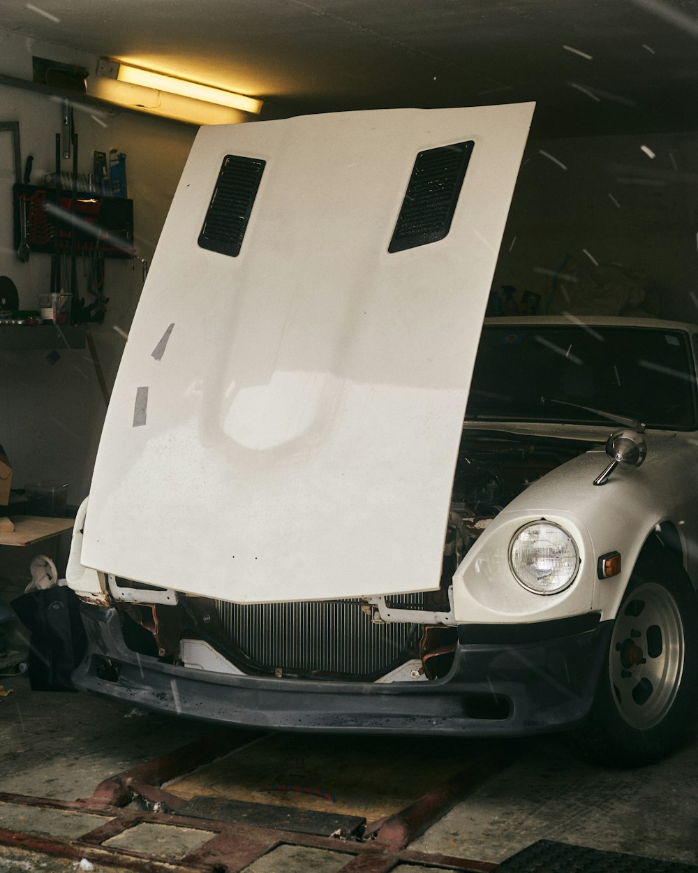 a white car with its hood open in a garage