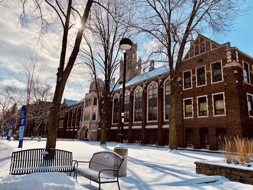 a bench sitting in the snow in front of a building
