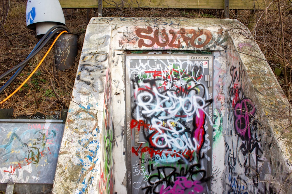 graffiti on a concrete structure near a trash can