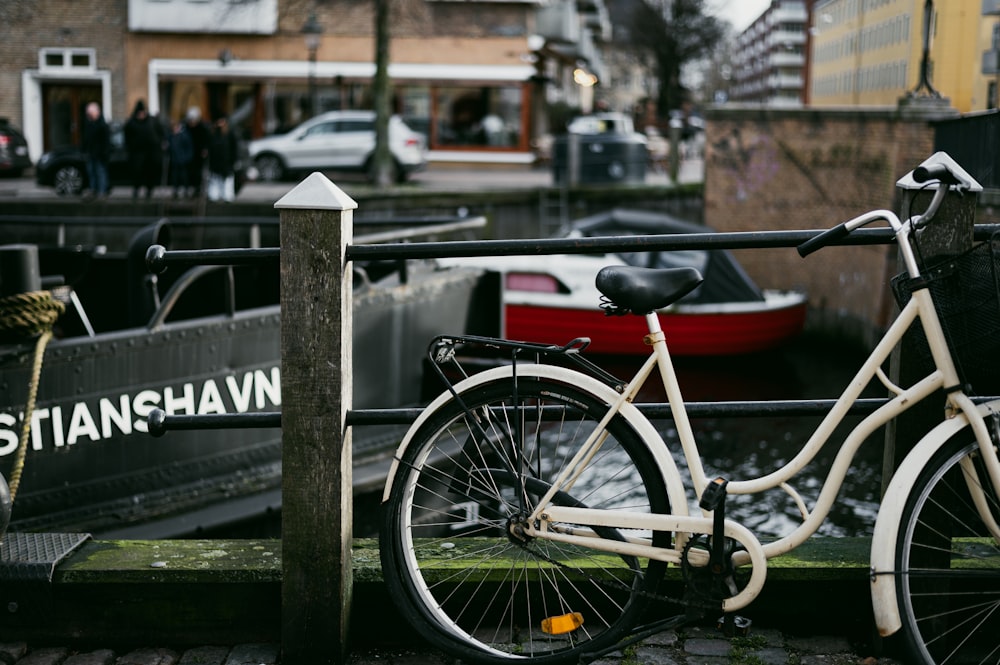 uma bicicleta branca estacionada ao lado de uma cerca de madeira