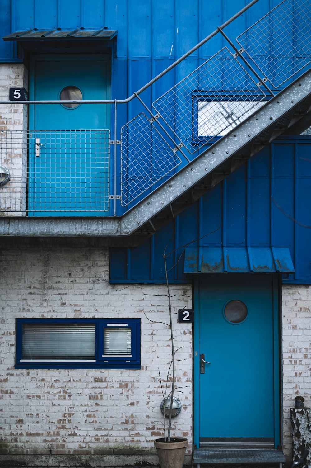 un bâtiment en brique avec une porte bleue et des escaliers