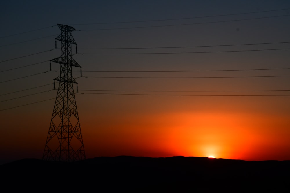 the sun is setting behind a power line