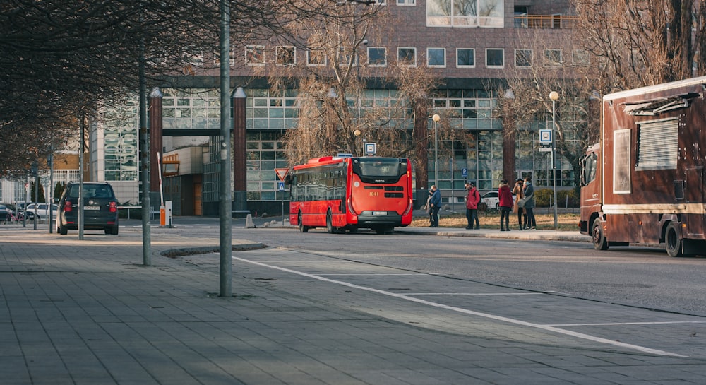 a red bus driving down a street next to tall buildings