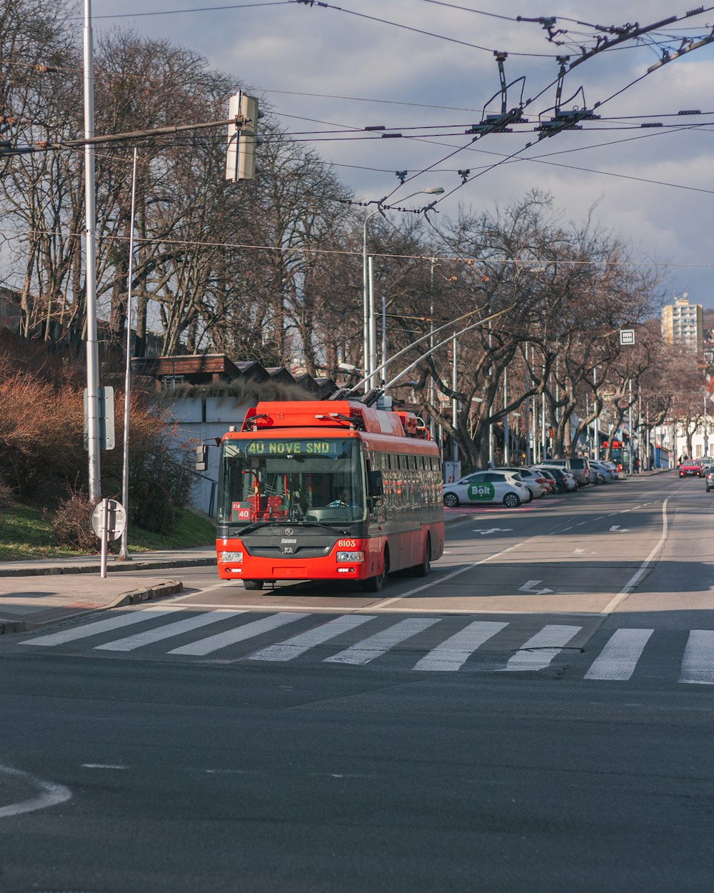 a red bus driving down a street next to tall buildings