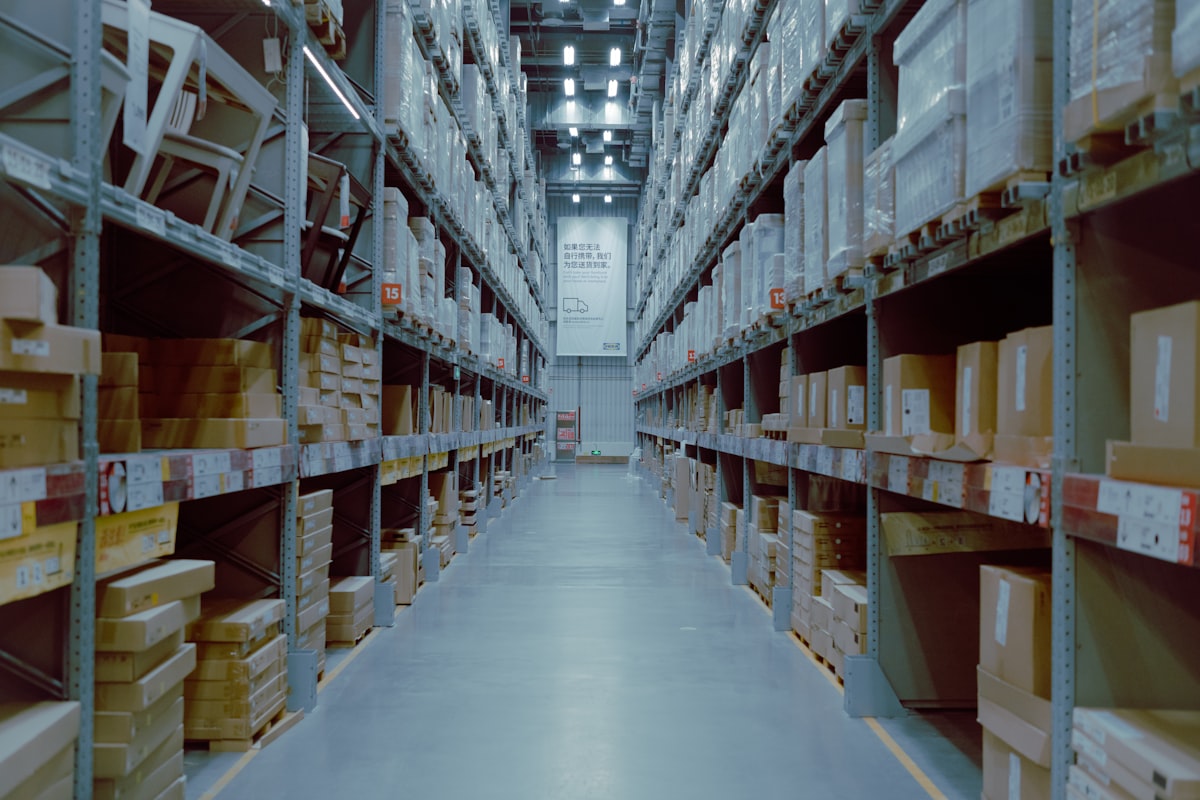 Interior of an industrial warehouse with tall shelving and corridor organization, representative of the layout required for pharmaceutical storage