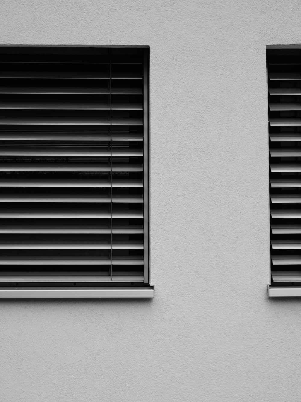 a black and white photo of two windows with blinds