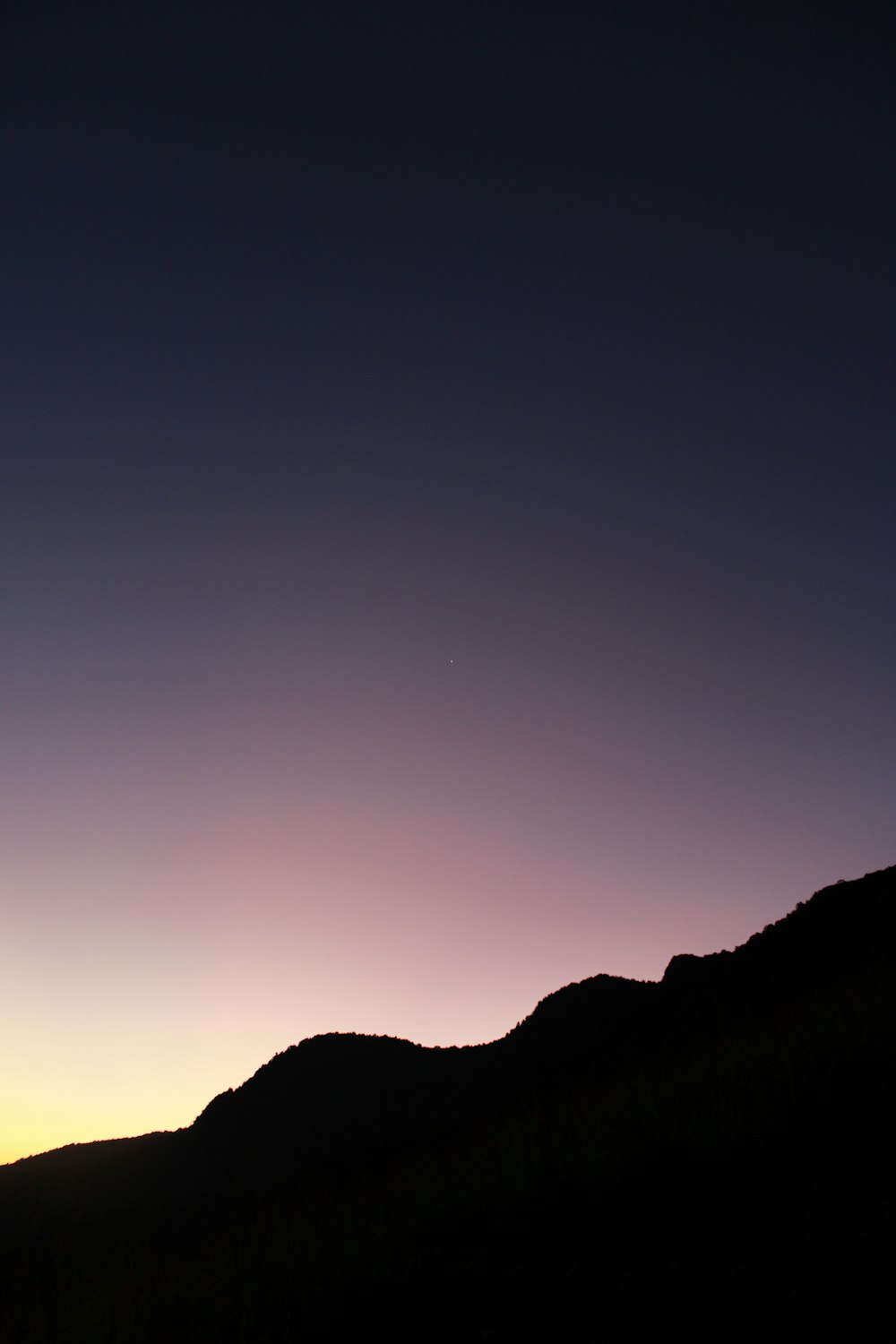 the silhouette of a person standing on top of a hill