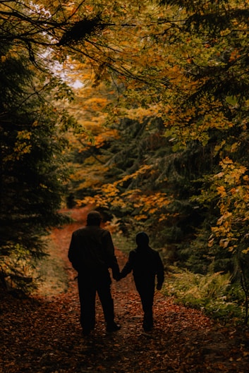 two people walking down a path in the woods